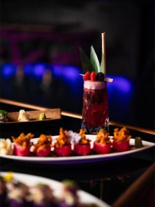 Cocktail with sushi rolls on table